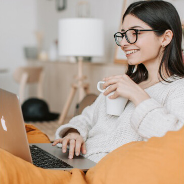 a young woman holding a coffee mug in front of her laptop
