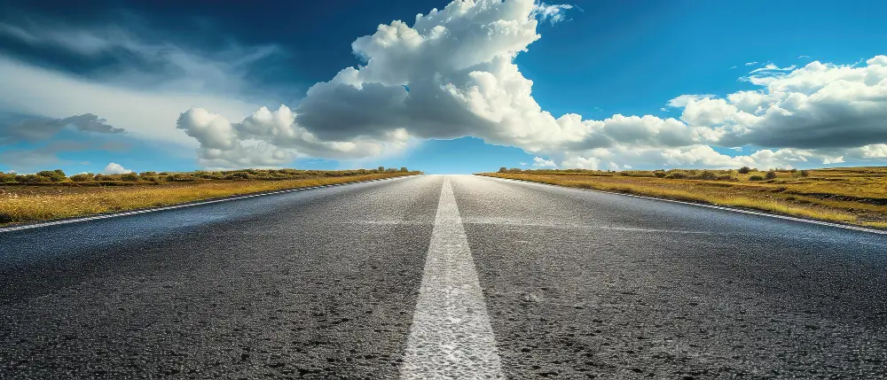 asphalt road ahead with blue skies and white clouds